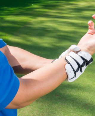 golfer holding their right wrist in their left hand with their palm facing up and fingers bent inward, used to explain golf injuries