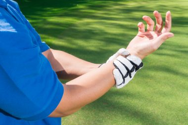 golfer holding their right wrist in their left hand with their palm facing up and fingers bent inward, used to explain golf injuries