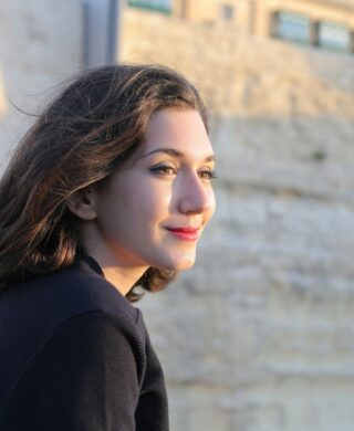 A young age woman smiling and looking off camera, used to explain mammograms age and when to start and stop
