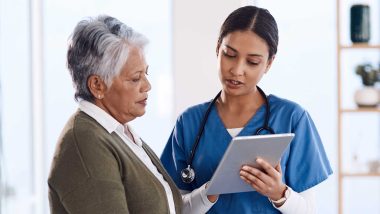 A medical professional pointing to a tablet and showing the tablet to an older woman, used to explain diagnostic mammogram