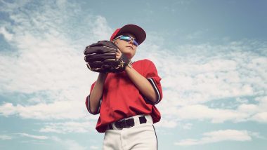 Photo of someone holding a baseball with a mitt and in a baseball uniform, used to explain shoulder injuries