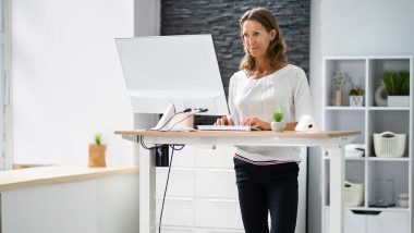 Woman working on computer at standing desk, used to explain how some jobs may contribute to varicose veins causes