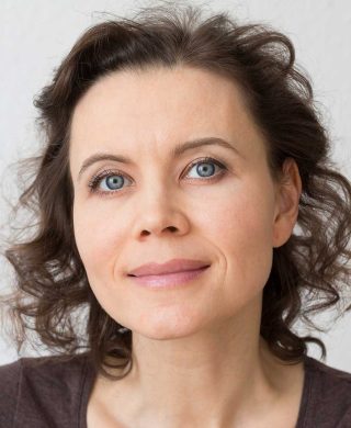 A middle aged woman with brown hair smiling at the camera, used to explain uterine fibroid facts