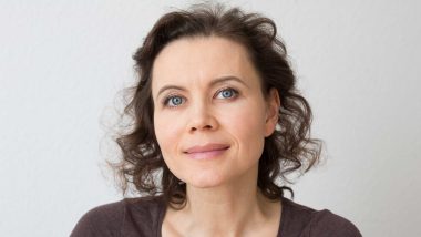 A middle aged woman with brown hair smiling at the camera, used to explain uterine fibroid facts