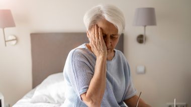 Older woman holding the side of her forehead with her hand, used to explain reasons why someone may need a head CT