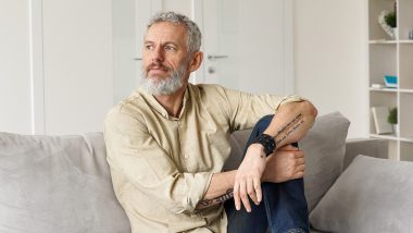 Gentleman with a white beard and hair sitting with his arms crossed over one leg and looking off camera, used to explain enlarged prostate treatment