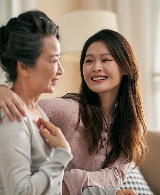 Two women sitting together on a couch with one woman's arm around the other's shoulders, used to explain BRCA gene testing