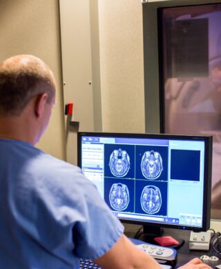 An imaging professional reviewing MRI scan data in front of a monitor