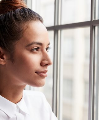 Young woman looking out an open window, used to explain breast cancer awareness