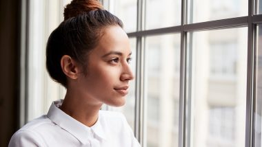 Young woman looking out an open window, used to explain breast cancer awareness