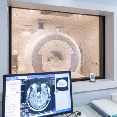 An MRI scanner in the background with a screen and the scan information in the foreground, used to explain MRI safety
