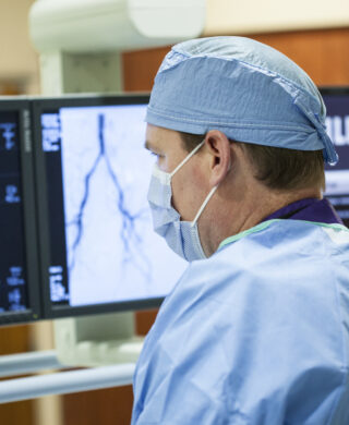 An interventional radiologist looks at monitors with scan information, used to explain imaging's role in aneurysm treatment
