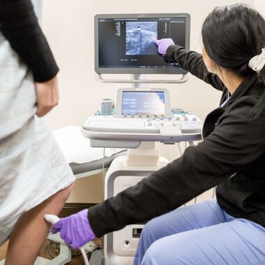 Photo of a vein provider using a tool on a patient's leg to identify vein problems like deep vein thrombosis or varicose veins