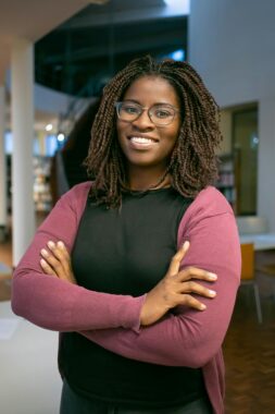 Photo of a woman smiling and posing for a photo with her arms crossed, used to explain dense breast tissue