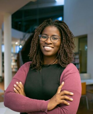 Photo of a woman smiling and posing for a photo with her arms crossed, used to explain dense breast tissue