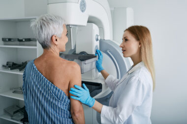 Older adult woman receives a mammogram with a technologist, used to help explain how a breast imaging center takes a mammogram